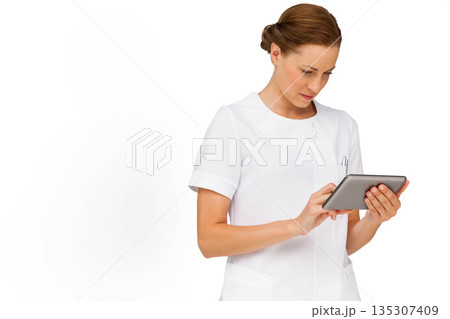 Female healthcare professional wearing medical uniform holding digital tablet in studio, copy space 135307409