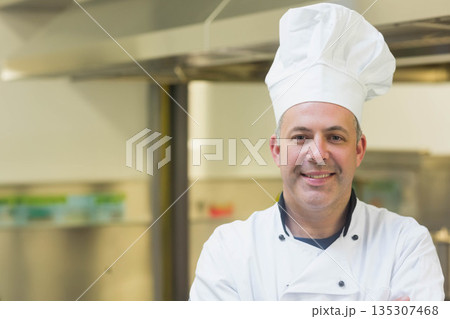 Male chef wearing white chef jacket and hat standing under vent hood in kitchen, copy space Male chef wearing white chef jacket and hat standing under vent hood in kitchen, copy space 135307468