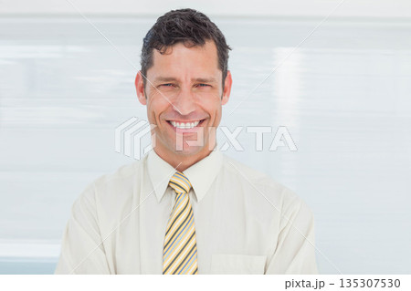 Mature adult male smiling while posing in office with striped necktie and horizontal blinds 135307530