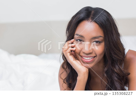 African American woman reclining on bed at home wearing sleeveless top with bedding, copy space African American woman reclining on bed at home wearing sleeveless top with bedding, copy space 135308227