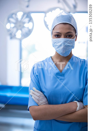 African American woman surgeon wearing scrubs standing under lights, arms crossed in operating room African American woman surgeon wearing scrubs standing under lights, arms crossed in operating room 135308289
