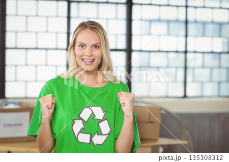Smiling adult female wearing green recycling T-shirt standing in warehouse sorting cardboard boxes Smiling adult female wearing green recycling T-shirt standing in warehouse sorting cardboard boxes 135308312