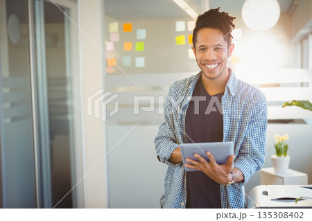 African American man wearing plaid shirt in office holding tablet near sticky notes, copy space African American man wearing plaid shirt in office holding tablet near sticky notes, copy space 135308402