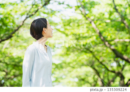並木で見上げている若い女性　ライフスタイルイメージ 135309224