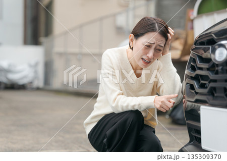 車の傷を確認する女性 135309370