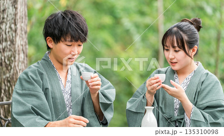 旅先で森林浴をしながら日本酒を飲む夫婦,カップル 旅先で森林浴をしながら日本酒を飲む夫婦,カップル 135310098