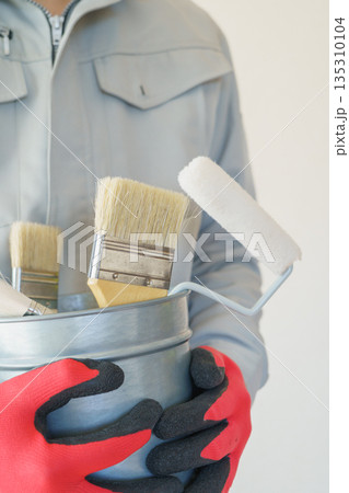刷毛やローラーの入ったバケツを持つ作業服の人｜リフォーム・塗装業者・DIY　イメージ 135310104