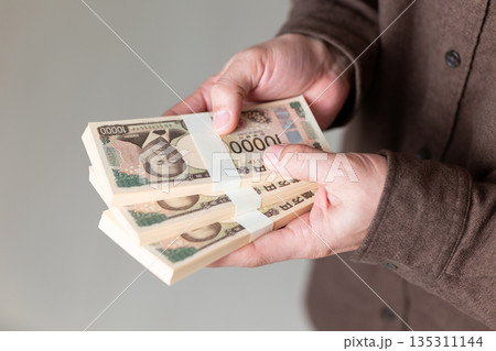 お金の札束を持つカジュアル姿のミドル男性ビジネスマン 135311144