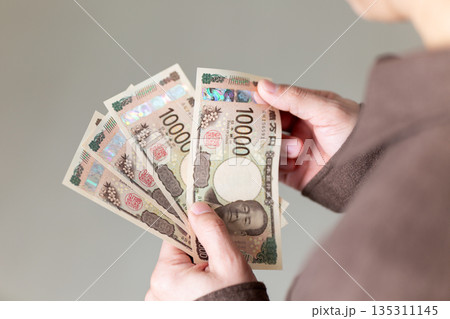 お金を持つカジュアル姿のミドル男性ビジネスマン 135311145