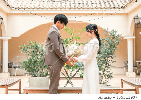 ブーケを持って見つめ合う新郎新婦(ウェディング・ブライダル・夫婦) ブーケを持って見つめ合う新郎新婦(ウェディング・ブライダル・夫婦) 135311907