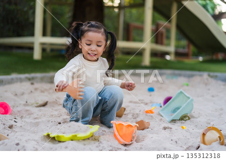 happy child girl playing sand with toy on playground happy child girl playing sand with toy on playground 135312318