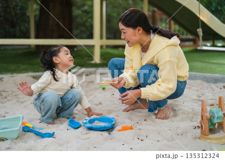 mother and child girl playing sand with toy on playground mother and child girl playing sand with toy on playground 135312324