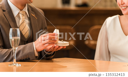 レストランでプロポーズをする男性と指輪を受け取る女性 レストランでプロポーズをする男性と指輪を受け取る女性 135312413