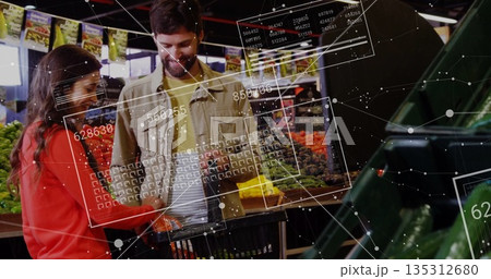 Examining couple selecting produce from open bins in produce aisle with basket, digital panels 135312680