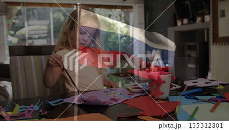 Painting preschool girl using brush on paper at dining table, with palette and markers Painting preschool girl using brush on paper at dining table, with palette and markers 135312801