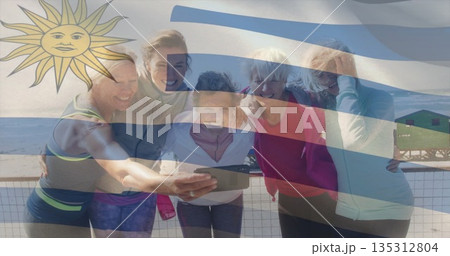 Smiling friends in sportswear taking smartphone selfie on beach railing, with lifeguard tower Smiling friends in sportswear taking smartphone selfie on beach railing, with lifeguard tower 135312804
