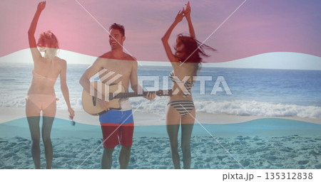Friends in bikinis and trunks strumming acoustic guitar singing into mic dancing on beach at sunset Friends in bikinis and trunks strumming acoustic guitar singing into mic dancing on beach at sunset 135312838