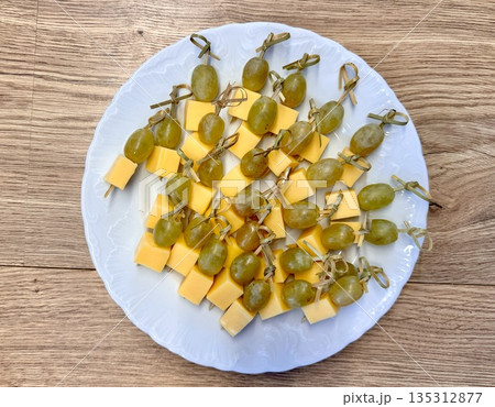New Year's snack skewers hard cheese with grapes on the festive table New Year's snack skewers hard cheese with grapes on the festive table 135312877