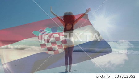 Holding woman wearing black top and white shorts standing on sandy beach, with Croatian flag Holding woman wearing black top and white shorts standing on sandy beach, with Croatian flag 135312952