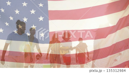 Walking group of five friends carrying acoustic guitar, football and cooler along beach at sunset 135312984