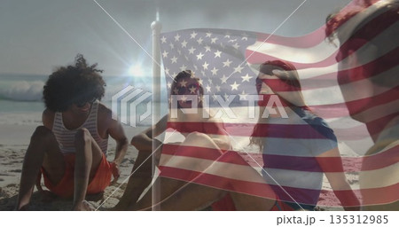 Sitting group of four friends wearing swimwear on sandy ocean shore at sunset, with flag overlay Sitting group of four friends wearing swimwear on sandy ocean shore at sunset, with flag overlay 135312985