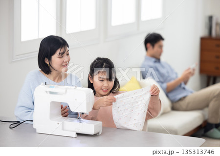 母親と一緒にミシンがけをする小学生の女の子 母親と一緒にミシンがけをする小学生の女の子 135313746