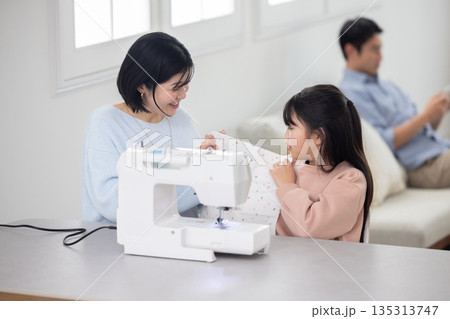 母親と一緒にミシンがけをする小学生の女の子 母親と一緒にミシンがけをする小学生の女の子 135313747