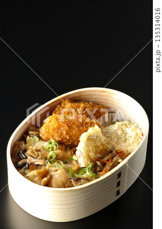きのこご飯とカキフライ弁当を黒背景で撮影 135314016