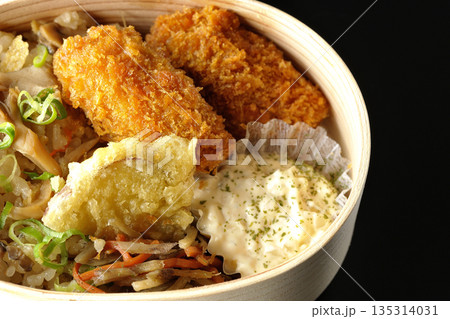 きのこご飯とカキフライ弁当を黒背景で撮影 135314031