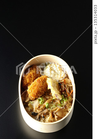 きのこご飯とカキフライ弁当を黒背景で撮影 きのこご飯とカキフライ弁当を黒背景で撮影 135314033