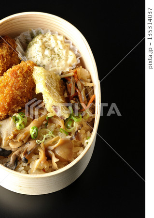 きのこご飯とカキフライ弁当を黒背景で撮影 135314037