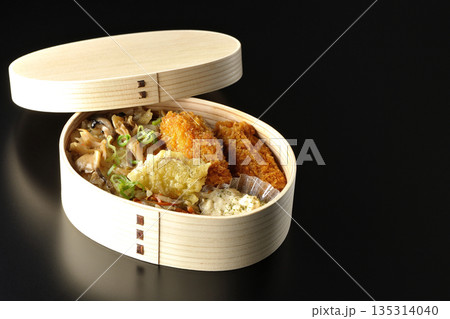 きのこご飯とカキフライ弁当を黒背景で撮影 135314040