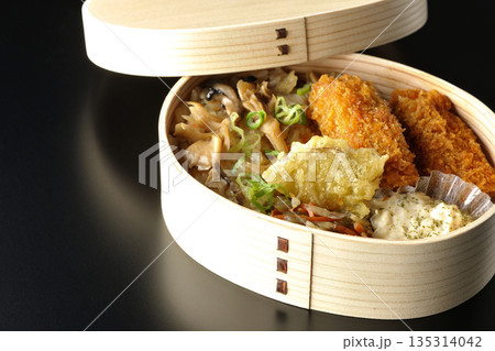 きのこご飯とカキフライ弁当を黒背景で撮影 135314042