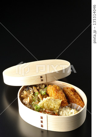 きのこご飯とカキフライ弁当を黒背景で撮影 135314046