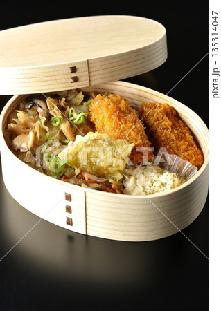 きのこご飯とカキフライ弁当を黒背景で撮影 135314047