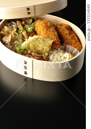 きのこご飯とカキフライ弁当を黒背景で撮影 135314049