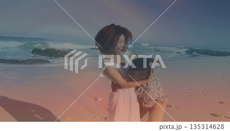 Embracing couple sharing moment on sunny beach shoreline, wearing flowing dress and patterned shirt Embracing couple sharing moment on sunny beach shoreline, wearing flowing dress and patterned shirt 135314628