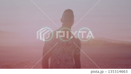 Standing male wearing floral shirt gazing across salt flat at sunset, with three glowing cyan rings Standing male wearing floral shirt gazing across salt flat at sunset, with three glowing cyan rings 135314663