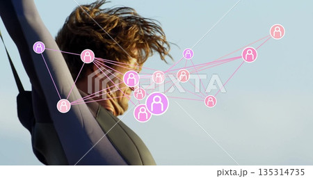 Man wearing full-body wetsuit raising arms overhead against pale blue sky, with pink network icons Man wearing full-body wetsuit raising arms overhead against pale blue sky, with pink network icons 135314735