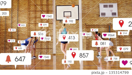 Dribbling white teenage girl maneuvering basketball on school gym court, with digital overlays 135314799