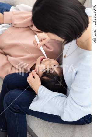 母親に歯を仕上げ磨きしてもらう小学生の女の子 母親に歯を仕上げ磨きしてもらう小学生の女の子 135315040