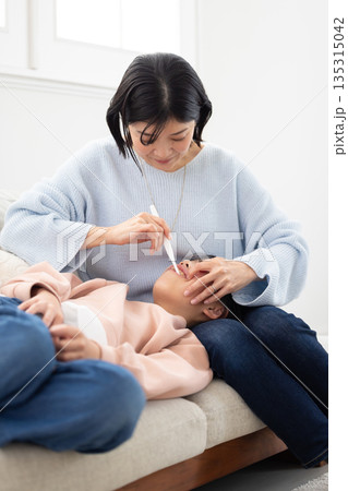 娘の歯を仕上げ磨きする母親 娘の歯を仕上げ磨きする母親 135315042