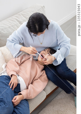母親に歯を仕上げ磨きしてもらう小学生の女の子 母親に歯を仕上げ磨きしてもらう小学生の女の子 135315043