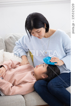 娘の額に氷嚢を当てる母親 娘の額に氷嚢を当てる母親 135315220
