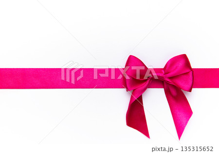 Pink satin ribbon forming bow on white background 135315652