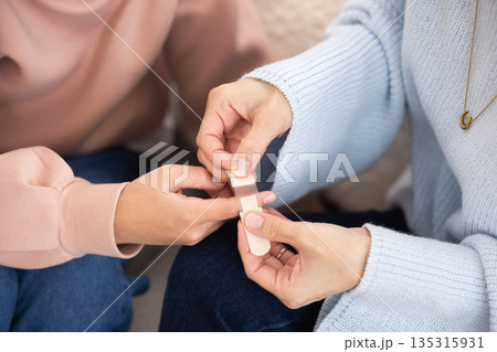子供の指に絆創膏を貼る母親の手元のクローズアップ 子供の指に絆創膏を貼る母親の手元のクローズアップ 135315931
