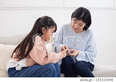 小学生の娘の指に絆創膏を貼る母親 135315940