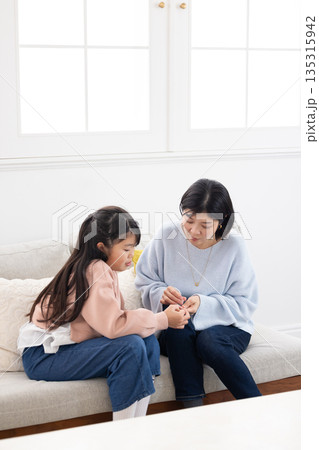 小学生の娘の指に絆創膏を貼る母親 小学生の娘の指に絆創膏を貼る母親 135315942