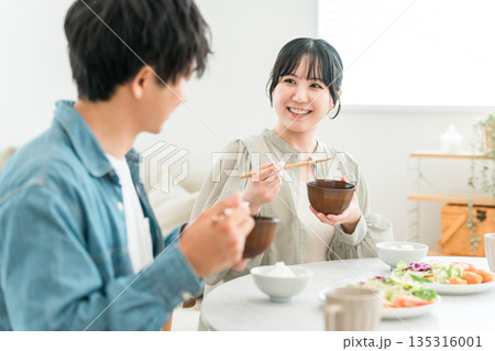 マイホームのダイニングテーブルで食事をする若いアジア人夫婦,カップル マイホームのダイニングテーブルで食事をする若いアジア人夫婦,カップル 135316001