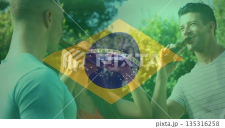 Toasting group of friends raising brown glass beer bottles in park under sunny Brazilian flag Toasting group of friends raising brown glass beer bottles in park under sunny Brazilian flag 135316258